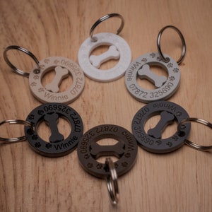 Puede incluir: Seis medallas para perros diferentes con una forma de hueso recortada en el centro. Las medallas son de varios colores, incluyendo negro, gris, marr&oacute;n y blanco. Cada medalla tiene el nombre "Winnie" y un n&uacute;mero de tel&eacute;fono grabado.