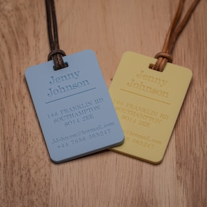 May include: Two blue and yellow rectangular name tags with a brown leather cord. The name tags have the name "Jenny Johnson" and the address "188 Franklin Rd Southampton SO14 2EE" along with an email address and phone number.