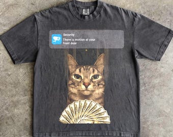 Puede incluir: Camiseta gris oscuro con un gato, un abanico de billetes y una alerta de seguridad que dice "Hay movimiento en tu puerta". La palabra "Pepper" está impresa en la parte inferior.