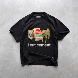 May include: Black t-shirt with a graphic of a cat looking at a stack of cement bags. The text "i eat cement" is printed below the image.