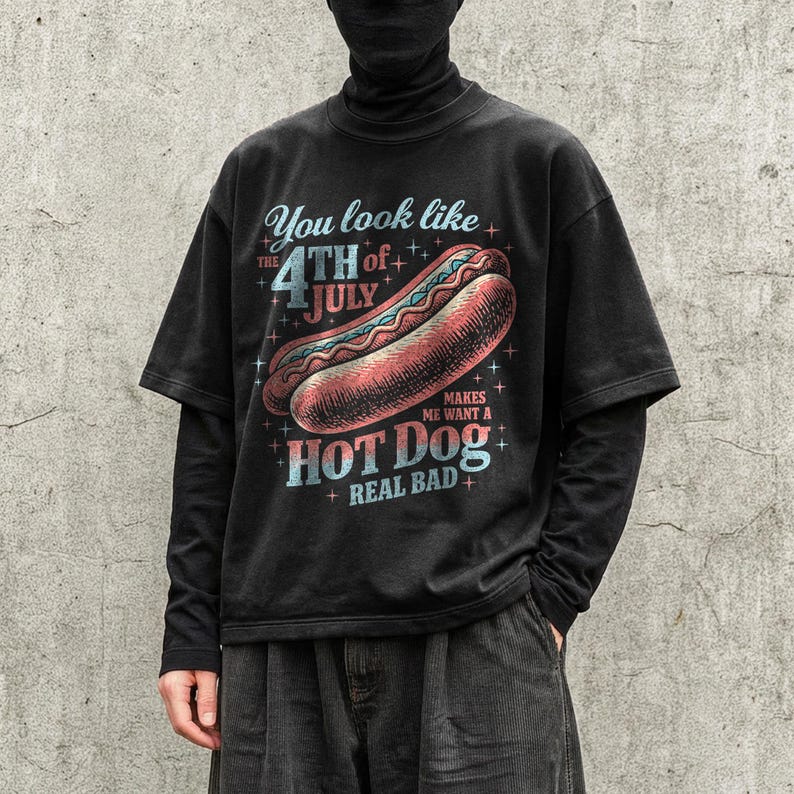 May include: Black graphic t-shirt with the text "You look like the 4th of July makes me want a hot dog real bad" and a hot dog illustration. The shirt has short sleeves and a vintage style.