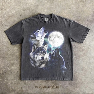 K&ouml;nnte beinhalten: Dunkelgraues T-Shirt mit einer Grafik von drei W&ouml;lfen, die den Vollmond anheulen. Das Design beinhaltet Blau-, Wei&szlig;- und Schwarzt&ouml;ne. Das Wort "PEPPER" ist am unteren Rand des Shirts aufgedruckt.