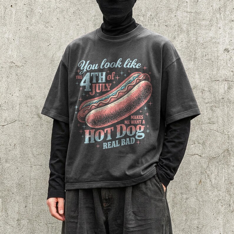 May include: Dark gray t-shirt with a distressed graphic of a hot dog and the text "You look like the 4th of July makes me want a hot dog real bad." The design features red, blue, and white colors.