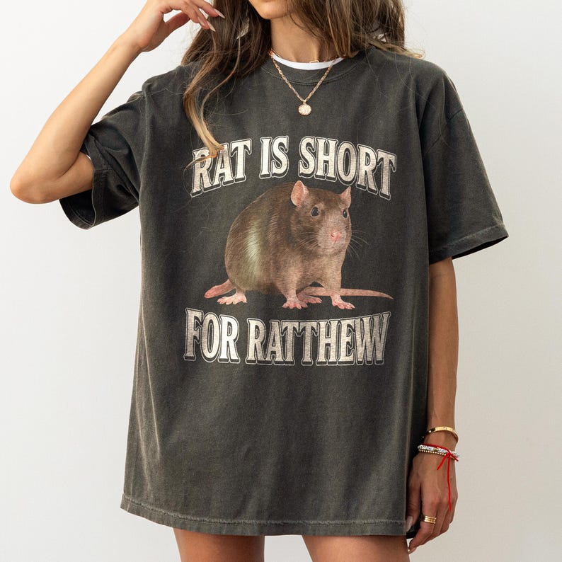 May include: A dark gray t-shirt with a graphic of a rat and the text "Rat is short for Ratthew".