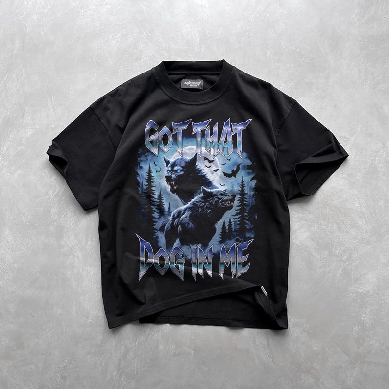 Pode incluir: Camiseta preta com estampa gr&aacute;fica de dois lobos uivando para a lua. O texto "GOT THAT DOG IN ME" est&aacute; impresso abaixo dos lobos.