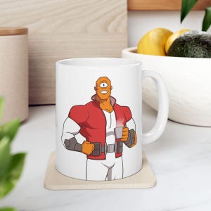 May include: White ceramic mug featuring a cartoon superhero with one eye, wearing a red jacket and holding a cup of coffee. The design is printed on the mug's surface, showcasing a bold and colorful illustration.