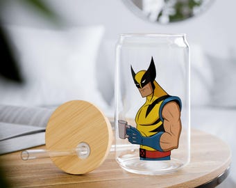 May include: A clear glass can-shaped tumbler featuring a graphic of the comic book character Wolverine in a yellow and blue suit holding a small mug. The set includes a round bamboo lid with a hole and a clear glass straw for drinking beverages.