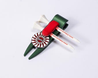 May include: Green golf ball holder with a red and white logo that says "BYRD" and the text "WWW.THEBYRD.COM". The holder has two white golf tees and a red golf ball marker.