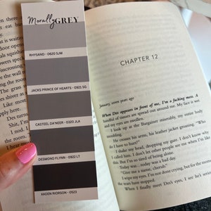 May include: A book open to Chapter 12, with the text "When Des appears in front of me, I'm a fucking mess."  A color chart with the names "Rhysand", "Jacks Prince of Hearts", "Casteel Da'neer", "Desmond Flynn", and "Xaden Riorson" is visible on the left side of the page.