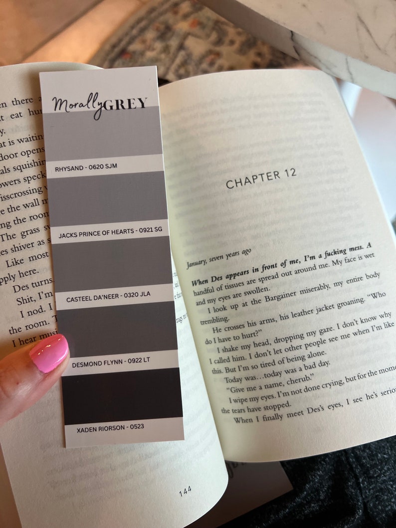 May include: A book open to Chapter 12, with the text "When Des appears in front of me, I'm a fucking mess."  A color chart with the names "Rhysand", "Jacks Prince of Hearts", "Casteel Da'neer", "Desmond Flynn", and "Xaden Riorson" is visible on the left side of the page.