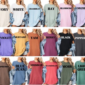 May include: A collection of 18 oversized t-shirts in various colors, each with a different color name printed on the front. The colors include Ivory, White, Chambray, Bay, Blossom, Orchid, Violet, Mustard, Yam, Berry, Black, Pepper, Espresso, Blue Jean, Crimson, Watermelon, Moss, and Light Green.