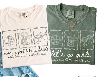 May include: Two t-shirts, one ivory and one moss green, with a graphic design. The design includes a disco ball, cowboy boots and hat, and champagne glasses. The ivory shirt says "man, I feel like a bride" and the green shirt says "let's go girls".