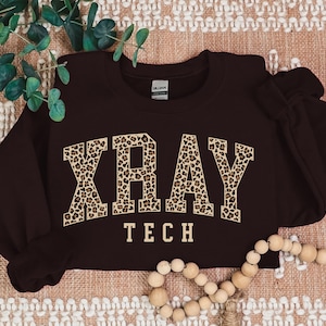 May include: A maroon sweatshirt with a leopard print "XRAY TECH" graphic.
