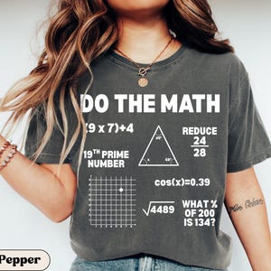 May include: Dark gray t-shirt with the text "DO THE MATH" and various mathematical equations and symbols. The shirt includes the text "19TH PRIME NUMBER" and "WHAT % OF 200 IS 134?"