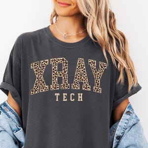 May include: A dark gray t-shirt with a leopard print "XRAY TECH" graphic.