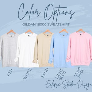 May include: A display of Gildan 18000 sweatshirts in various colors: ash, white, sand, light blue, and light pink. The text "Color Options" and "Eclipse Studio Design" are also visible.