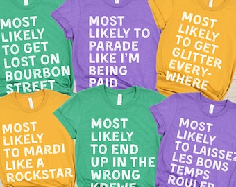 May include: A collection of colorful t-shirts with white text. The shirts are in shades of green, purple, and gold. Each shirt has a different phrase related to Mardi Gras, such as "Most Likely to Get Lost on Bourbon Street."