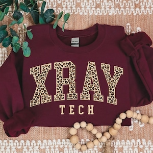 May include: Burgundy sweatshirt with the word "XRAY" in leopard print letters and the words "TECH" underneath.