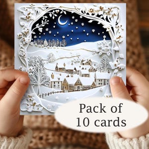 May include: A white, layered paper Christmas card featuring a winter village scene under a starry night sky with a crescent moon. The card has intricate cut-out details and the text "Pack of 10 cards" in a white oval.