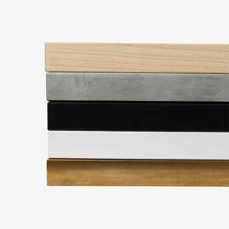 May include: A stack of five rectangular wooden frames in various colors. The colors include natural wood, gray, black, white, and gold. The frames are stacked horizontally, showcasing their different finishes.