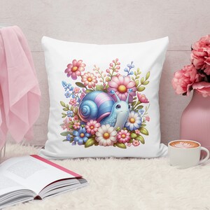 May include: A white pillow with a colorful illustration of a snail surrounded by pink, blue, and white flowers. The snail has a blue shell with pink accents and a light blue body.