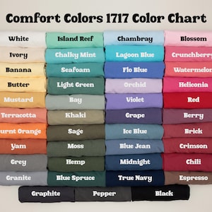 May include: Colour chart displaying 36 different shades of Comfort Colors 1717 fabric. The colours are arranged in rows of four, with each row representing a different colour family. The colour names are printed below each swatch.
