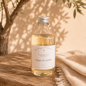 Peut inclure: Une bouteille en verre transparent remplie d'un liquide jaune clair, avec un bouchon à vis argenté et une étiquette blanche portant l'inscription Ma Bougie Bordelaise, Recharge parfum d'ambiance, Nuage de Vanille, 250 ml, Fabriqué en France.