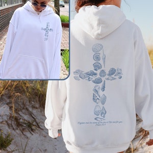 May include: White hooded sweatshirt with a blue seashell cross design on the back. The text "More than the sand of the sea is His love for you. Psalm 139:18" is printed below the cross.