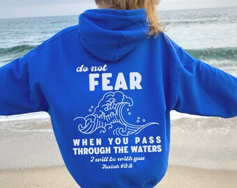 May include: Royal blue hooded sweatshirt with white text that reads "do not FEAR WHEN YOU PASS THROUGH THE WATERS I will be with you Isaiah 43:2" and a white wave graphic.