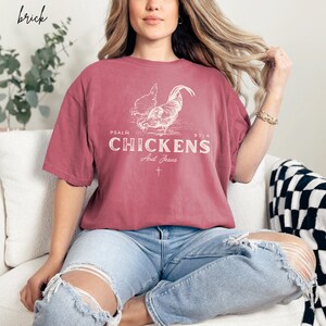 May include: A red t-shirt with a white graphic of two chickens and the text "PSALM 91:4 CHICKENS And Jesus".