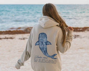 May include: A light beige hoodie with a blue whale graphic on the back. The whale has a starry pattern and the text "Psalm 146:6 HE IS THE MAKER OF HEAVEN AND EARTH. THE SEA AND EVERYTHING IN THEM-HE REMAINS FAITHFUL FOREVER." is printed below the whale.