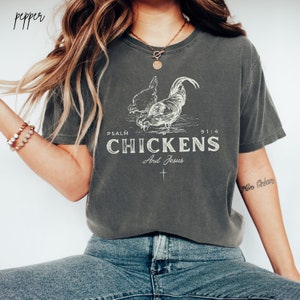 May include: A gray t-shirt with a white graphic of two chickens and the text "PSALM 91:4 CHICKENS And Jesus".