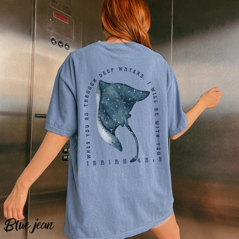 May include: Blue jean colored t-shirt with a large illustration of a stingray. The text on the shirt reads "When you go through deep waters, I will be with you."