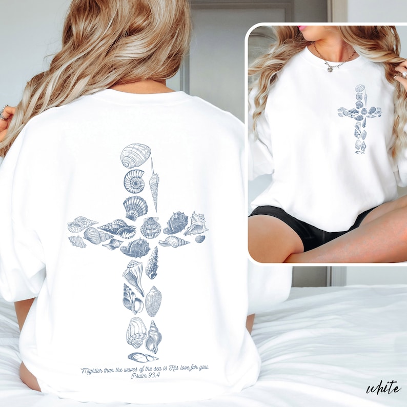 May include: White sweatshirt featuring a cross design made of seashells. The back of the sweatshirt has a larger cross design, while the front has a smaller version. The text "Mightier than the waves of the sea is His love for you Psalm 93.4" is printed on the back.