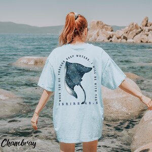 May include: Light blue t-shirt with a watercolor-style stingray design on the back. The text reads "WHEN YOU GO THROUGH DEEP WATERS, I WILL BE WITH YOU." The word "Chambray" is printed at the bottom.