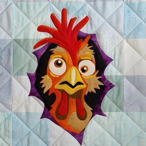 Peut inclure: Une tenture murale matelassée avec un motif de coq coloré. La tête du coq jaillit d'un trou bordé de violet au centre du quilt. Le quilt présente un motif patchwork dans les tons de bleu, vert et blanc.