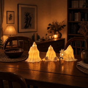 A zoomed-out view of the glowing chicken ghost trio on a table in a cozy, dark room at night. All three avian characters are glowing softly, radiating a whimsigoth delight. These funny glowing fowl serve as a cute spooky led lamp set, offering incredible weirdcore room decor and cozy witchy accents. A true pastel goth oddity, each macabre desk bird enhances your alt dark aesthetic. Find your goblincore dopamine with these unique whimsigoth gifts, perfect as glowing fairy garden items.