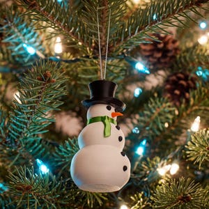The snowman ornament glowing against a Christmas tree strung with icy blue fairy lights, its pitted snow-white body catching the soft winter light.