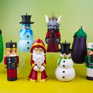 All eight Naughty and Nice stash ornaments arranged against a yellow-green background, a playful lineup of Christmas dopamine decor including the snowman, pickle, nutcracker, and Krampus.