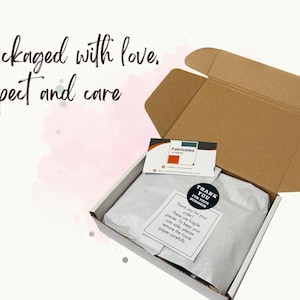 May include: An open cardboard shipping box containing items wrapped in white tissue paper. A business card with the text Fabricated, a round black Thank You sticker, and a square note with instructions to remove tissue paper carefully are included.