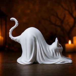 A right-side profile of the stretching ghost cat statue, showing its curly tail. This piece acts as a creepy cute fall decoration on a wooden mantle.