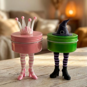 May include: Two decorative jars with legs. One is pink with a crown, the other is green with a witch hat. The pink jar has pink and white striped legs and pink high heels. The green jar has black boots and purple and black striped legs.