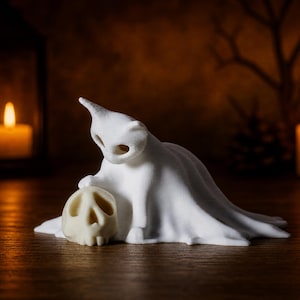 A close-up of the small kitten ghost cat resting its paw on a tiny skull, sitting on a wooden surface with a soft candlelight background, perfect for a witchy autumn vibe.