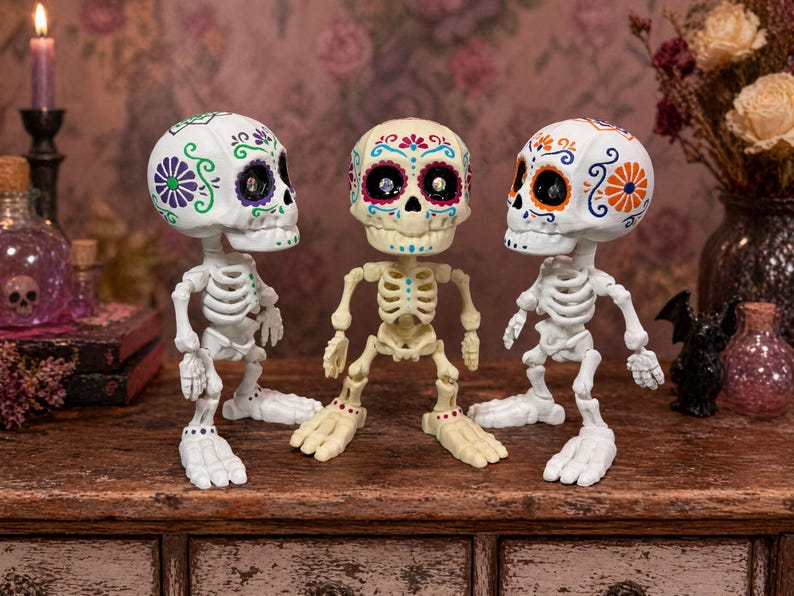 A trio of articulated skeletons where the center figure looks directly at the camera while the other two gaze inward. This image perfectly highlights the contrast between the natural bone and pure white color options of this sugar skull figure. An excellent gothic home accent and weirdcore desk fidget toy. This creepy cute pastel goth desk buddy is an engaging tactile sensory item, serving as a unique coworker gag gift and fun dopamine decor.