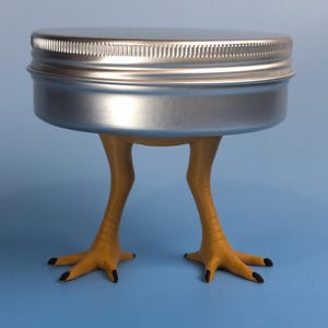 May include: A round, silver-colored metal tin with a screw-top lid, supported by two yellow, textured bird-like legs with black-tipped claws. The container is positioned upright, showcasing a metallic finish and realistic avian-inspired limbs.
