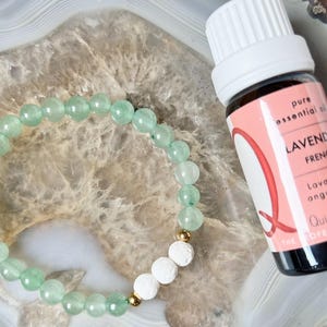May include: A green jade stone bracelet with gold accents and white lava beads. A bottle of pure essential oil labelled "Lavender French" is in the background.