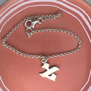 May include: A silver chain bracelet with a silver pendant shaped like the Hebrew letter 'Heh'.