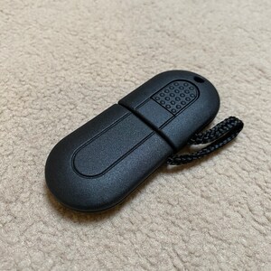 May include: A black USB drive with a textured surface and a small loop for attaching a lanyard. The drive is shaped like a capsule.