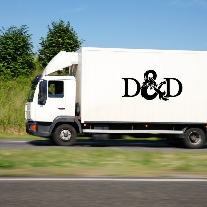 May include: A white delivery truck with the letters "D&D" in black, accompanied by a dragon graphic. The truck is on a road with green grass and trees in the background, under a blue sky.
