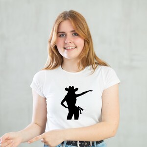 May include: A white t-shirt with a black silhouette of a woman wearing a cowboy hat and a skirt.